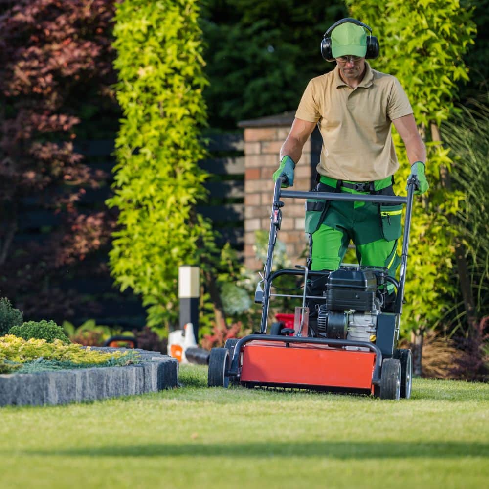 A worker perform landscaping services on a lawn.